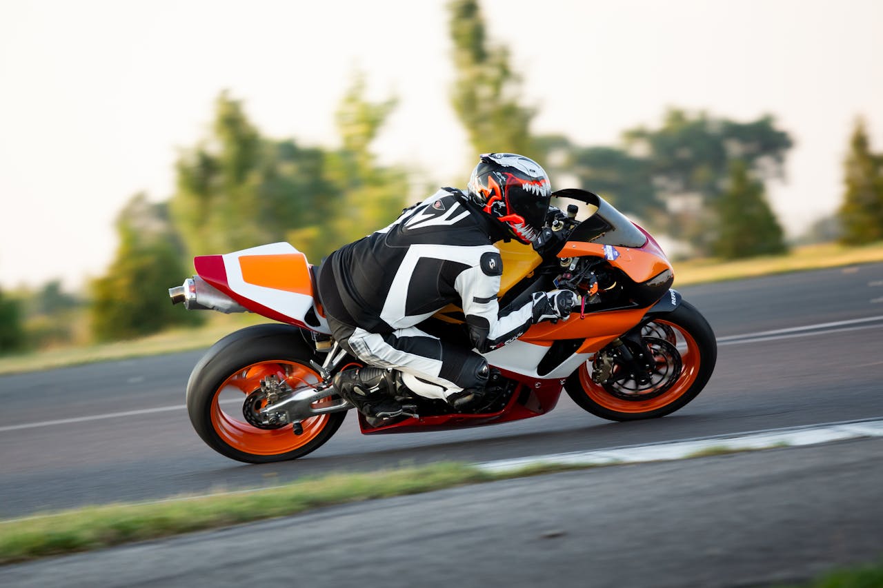 A rider in full gear racing a sports motorcycle on a track, showcasing speed and precision.